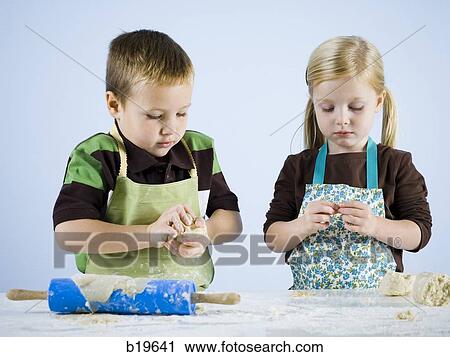 Stock Image - boy and girl kneading dough. Fotosearch