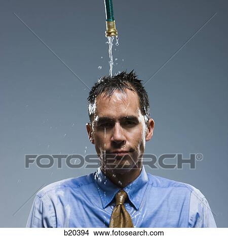 Picture - businessman standing under a hose. Fotosearch