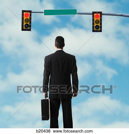 Stock Photo - businessperson standing at a traffic signal. Fotosearch
