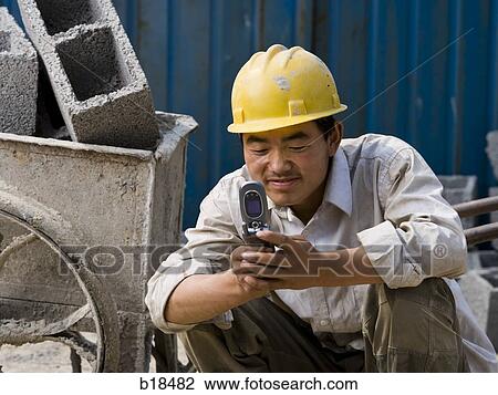 Construction worker looking at his cell phone. View Large Photo Image Stock Image - Construction worker looking at his cell phone.. Fotosearch