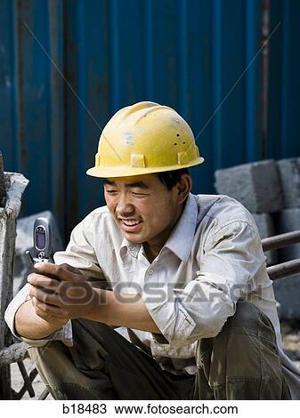 Construction worker looking at his cell phone. View Large Photo Image Stock Image - Construction worker looking at his cell phone.. Fotosearch