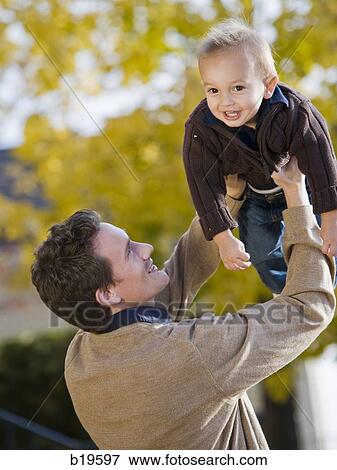 Stock Photo - dad lifting baby boy in the air. Fotosearch