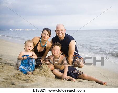 Stock Image - Family of four on the beach.. Fotosearch