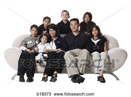 Family sitting on a couch smiling. View Large Photo Image Stock Image - Family sitting on a couch smiling.. Fotosearch
