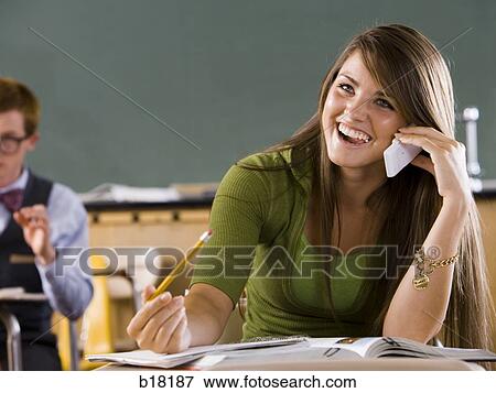 Stock Photo - Female student in a classroom on a cell phone.. Fotosearch
