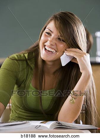 Stock Photo - Female student in a classroom on a cell phone.. Fotosearch