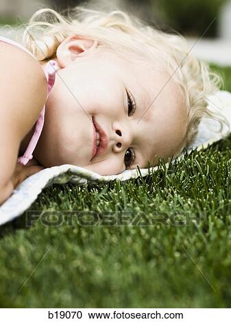 little girl lying on a blanket on the grass. View Large Photo Image Stock Image - little girl lying on a blanket on the grass.. Fotosearch