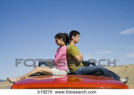 Stock Photography - man and woman next to a red convertible. Fotosearch