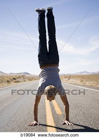 Picture - man doing a handstand in the middle of the road.. Fotosearch