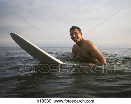 Stock Image - Man in the water with surfboard.. Fotosearch