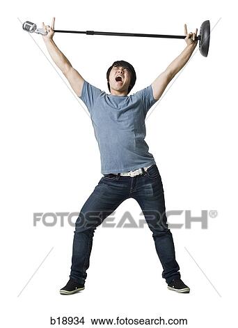 Picture - Man rocking out with mic stand.. Fotosearch