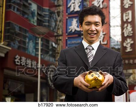 Man standing on a city street with a piggy bank. View Large Photo Image Stock Image - Man standing on a city street with a piggy bank.. Fotosearch