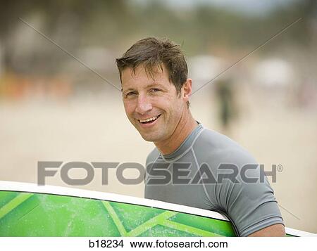 Picture - Man with surfboard at the beach.. Fotosearch