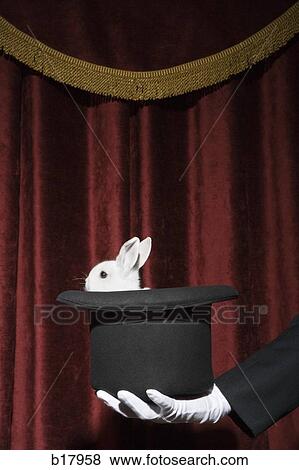 Stock Photo - Pulling a rabbit out of a hat.. Fotosearch