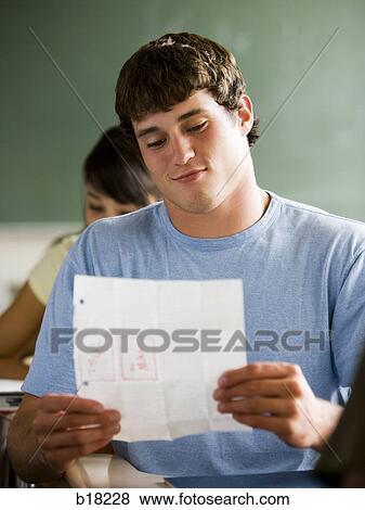 Stock Photo - Student reading notes in a classroom.. Fotosearch
