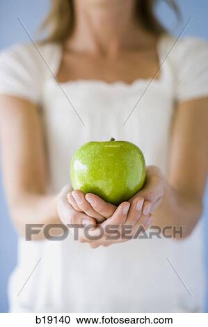 Stock Image - woman holding a green apple.. Fotosearch