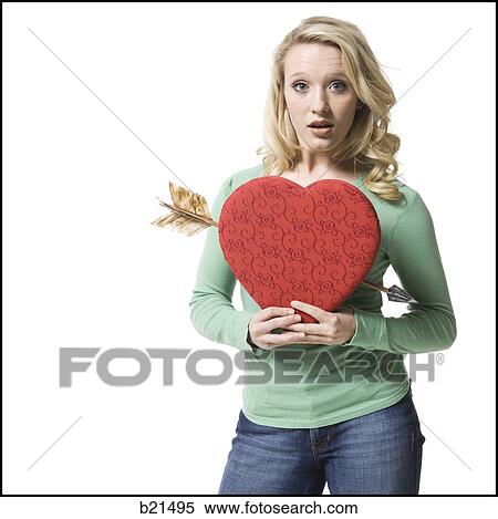 woman holding a heart with an arrow through it View Large Photo Image Stock Photography - woman holding a heart with an arrow through it. Fotosearch