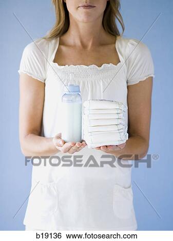 Stock Photograph - Woman holding diapers and a bottle.. Fotosearch