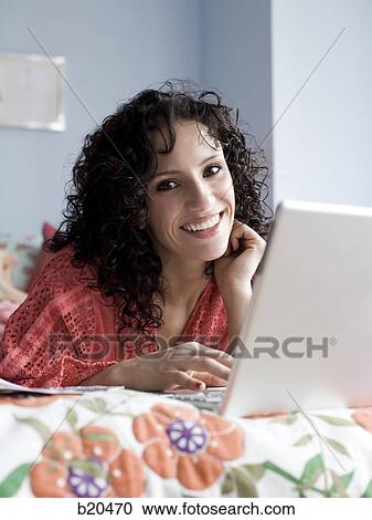 woman lying on a bed with a notebook computer View Large Photo Image Stock Image - woman lying on a bed with a notebook computer. Fotosearch
