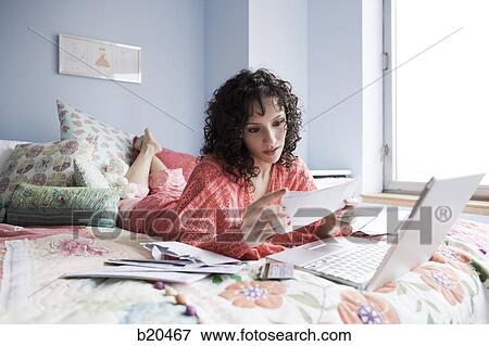 woman lying on a bed with a notebook computer View Large Photo Image Stock Photo - woman lying on a bed with a notebook computer. Fotosearch
