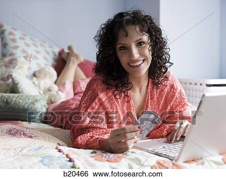 woman lying on a bed with a notebook computer View Large Photo Image Stock Photograph - woman lying on a bed with a notebook computer. Fotosearch