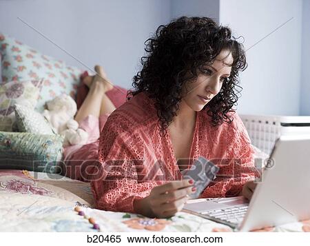 woman lying on a bed with a notebook computer View Large Photo Image Stock Photography - woman lying on a bed with a notebook computer. Fotosearch