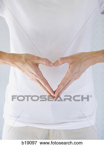 Stock Photo - Woman making a heart shape with her hands.. Fotosearch