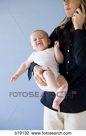 Woman on a cell phone holding a baby. View Large Photo Image Stock Image - Woman on a cell phone holding a baby.. Fotosearch