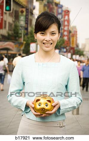 Woman standing on a city street with a piggy bank. View Large Photo Image Stock Image - Woman standing on a city street with a piggy bank.. Fotosearch