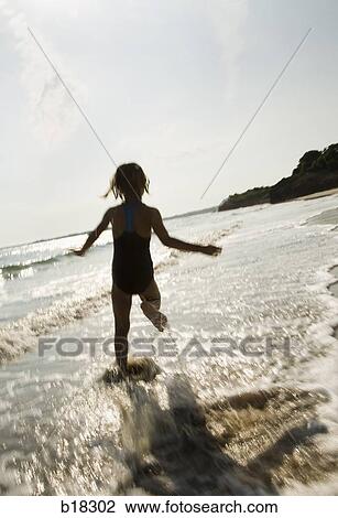 Stock Image - Young girls running in the surf.. Fotosearch