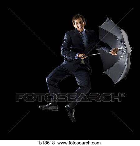 Stock Photo - Young man holding an umbrella and jumping.. Fotosearch