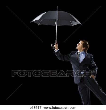 Young man holding an umbrella. View Large Photo Image Stock Photo - Young man holding an umbrella.. Fotosearch