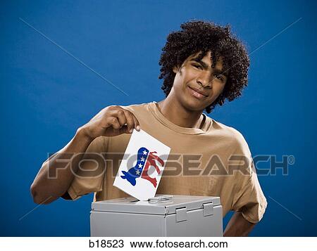 Stock Image - young man in a brown shirt casting a ballot.. Fotosearch
