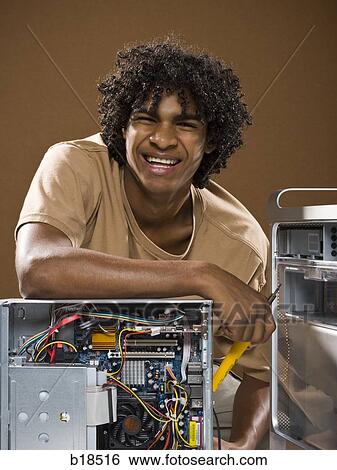 young man in a brown shirt fixing a computer. View Large Photo Image Stock Photograph - young man in a brown shirt fixing a computer.. Fotosearch