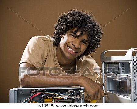 young man in a brown shirt fixing a computer. View Large Photo Image Stock Photography - young man in a brown shirt fixing a computer.. Fotosearch