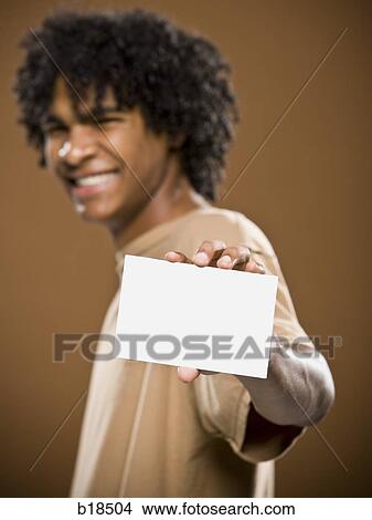 young man in a brown shirt holding a note card. View Large Photo Image Picture - young man in a brown shirt holding a note card.. Fotosearch