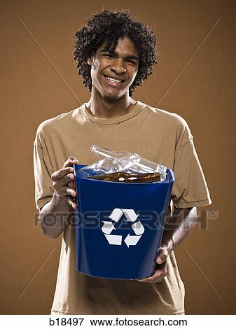 young man in a brown shirt holding a recycling bin. View Large Photo Image Stock Photo - young man in a brown shirt holding a recycling bin.. Fotosearch