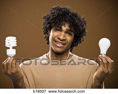 young man in a brown shirt holding light bulbs. View Large Photo Image Stock Photo - young man in a brown shirt holding light bulbs.. Fotosearch