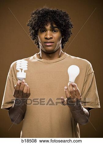 young man in a brown shirt holding light bulbs. View Large Photo Image Stock Photo - young man in a brown shirt holding light bulbs.. Fotosearch