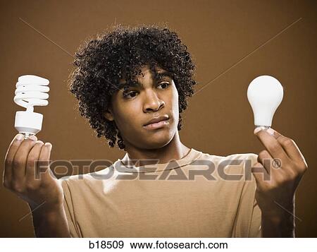 Stock Photo - young man in a brown shirt holding light bulbs.. Fotosearch