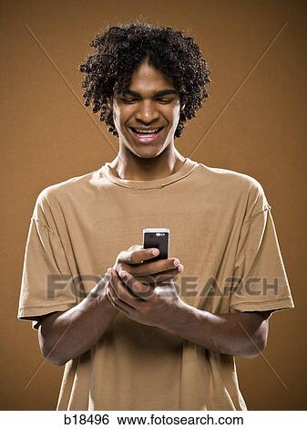 young man in a brown shirt on a cell phone. View Large Photo Image Stock Photograph - young man in a brown shirt on a cell phone.. Fotosearch