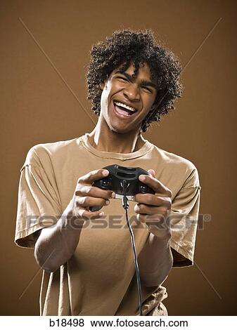 young man in a brown shirt playing a video game. View Large Photo Image Stock Photo - young man in a brown shirt playing a video game.. Fotosearch