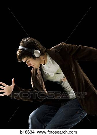 Young man listening to earphones and dancing. View Large Photo Image Picture - Young man listening to earphones and dancing.. Fotosearch