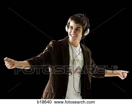Young man listening to earphones and dancing. View Large Photo Image Stock Image - Young man listening to earphones and dancing.. Fotosearch