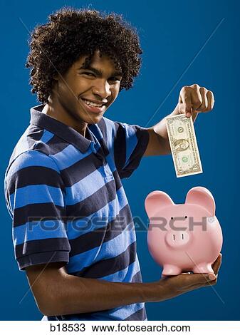 young man putting money in a piggy bank. View Large Photo Image Stock Image - young man putting money in a piggy bank.. Fotosearch
