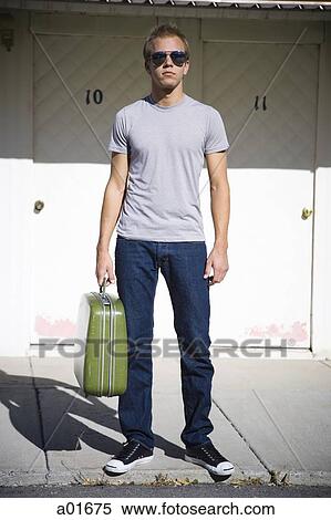 Young man standing with a suitcase. View Large Photo Image Stock Photography - Young man standing with a suitcase.. Fotosearch