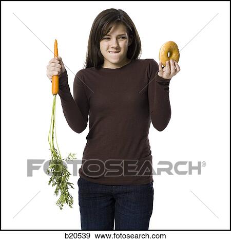 Stock Photo - young woman choosing between a carrot and a donut. Fotosearch