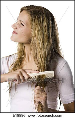 Stock Photograph - Young woman combing hair.. Fotosearch