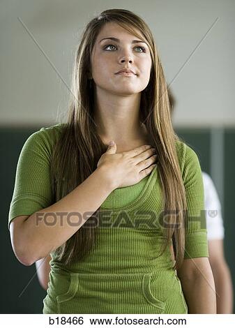 Young woman in a classroom with hand over heart. View Large Photo Image Stock Photograph - Young woman in a classroom with hand over heart.. Fotosearch
