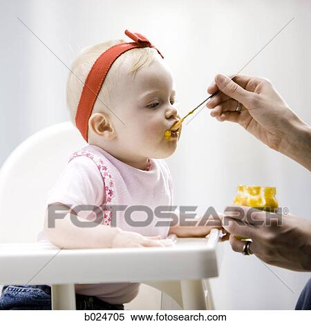 Stock Photography - baby girl in a high chair. Fotosearch